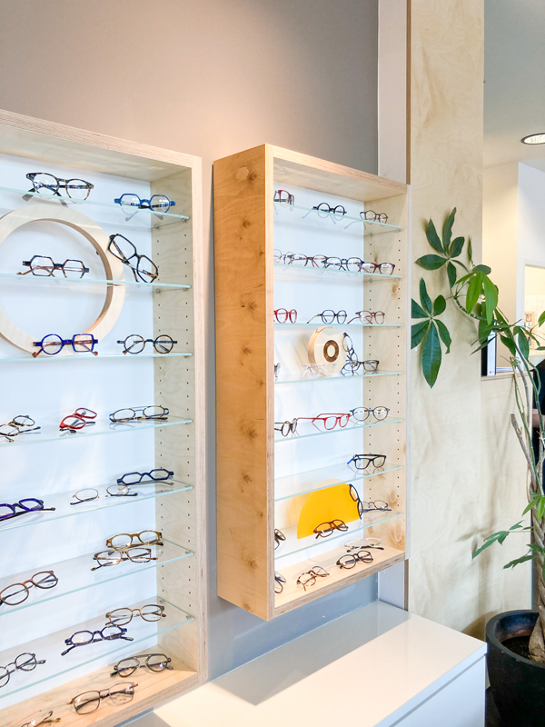 vue sur le linéaire de présentation de lunette d'un opticien, agencement sur-mesure réalisé en bois clair de bouleau, Design moderne, géométrique et coloré, Retail Design et réalisation par Studio Superstrate à Toulouse